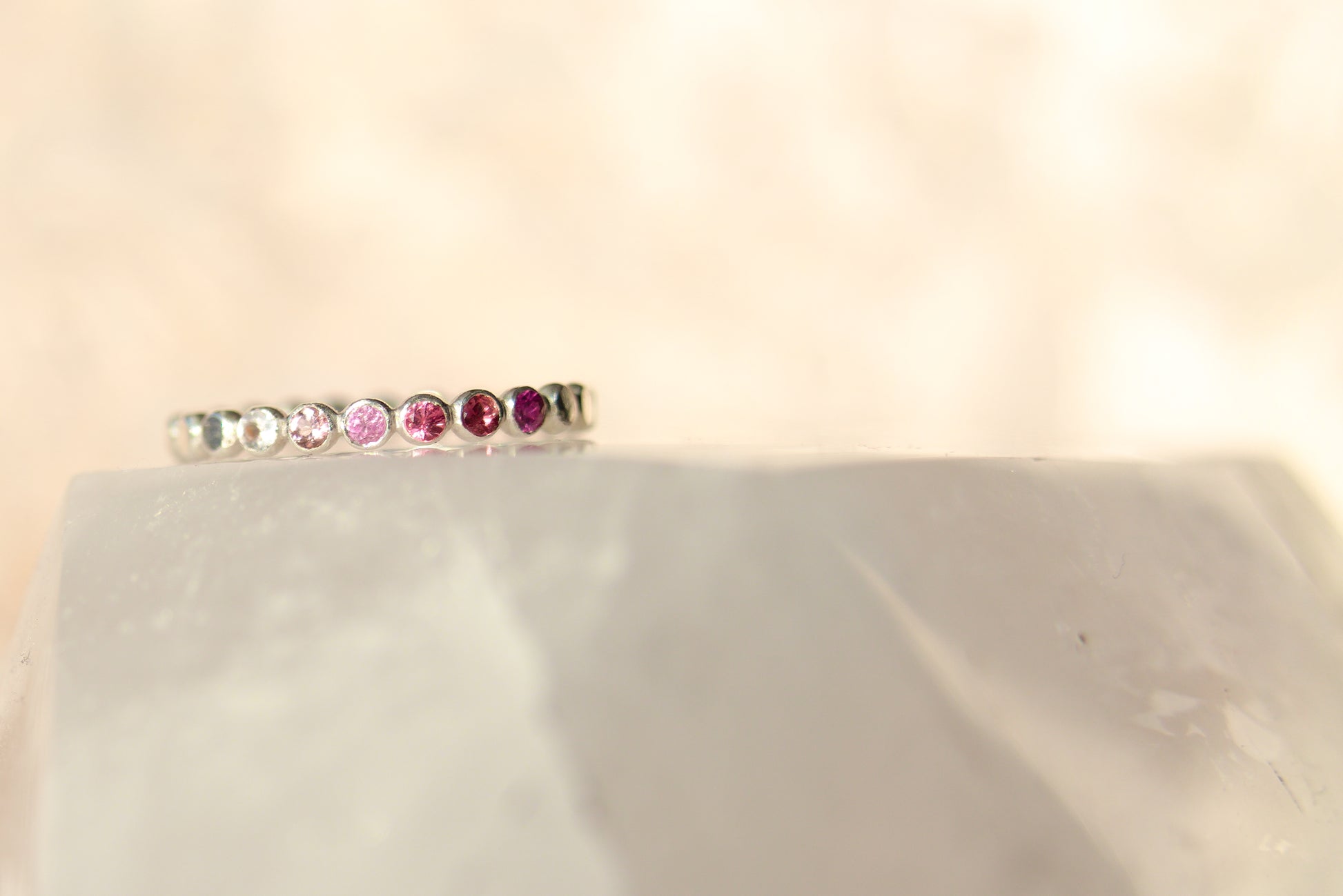 Silver ring with colorful gemstones on a light beige background