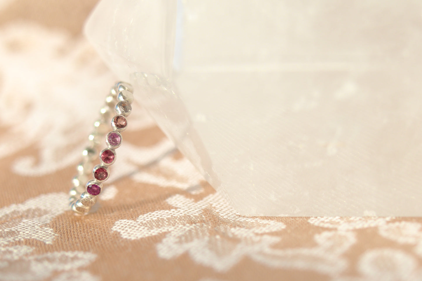 Silver earring with red gemstones on a lace fabric background