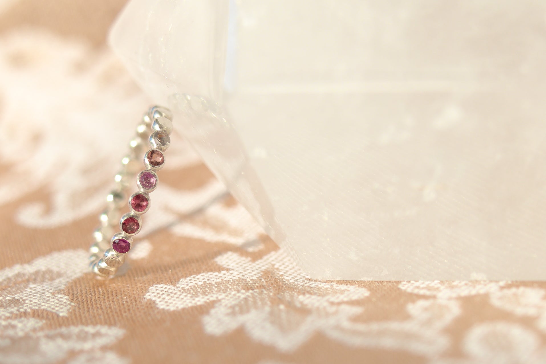 Silver earring with red gemstones on a lace fabric background